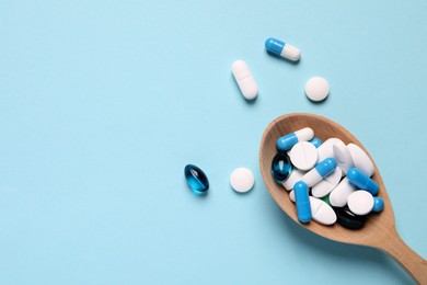 Photo of Many different pills and spoon on light blue background, flat lay. Space for text