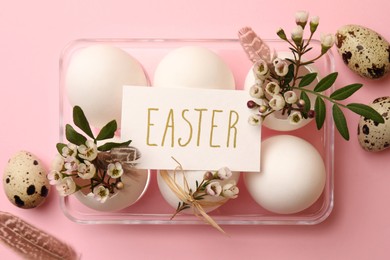 Flat lay composition with chicken eggs, natural decor and word Easter on pink background. Happy celebration