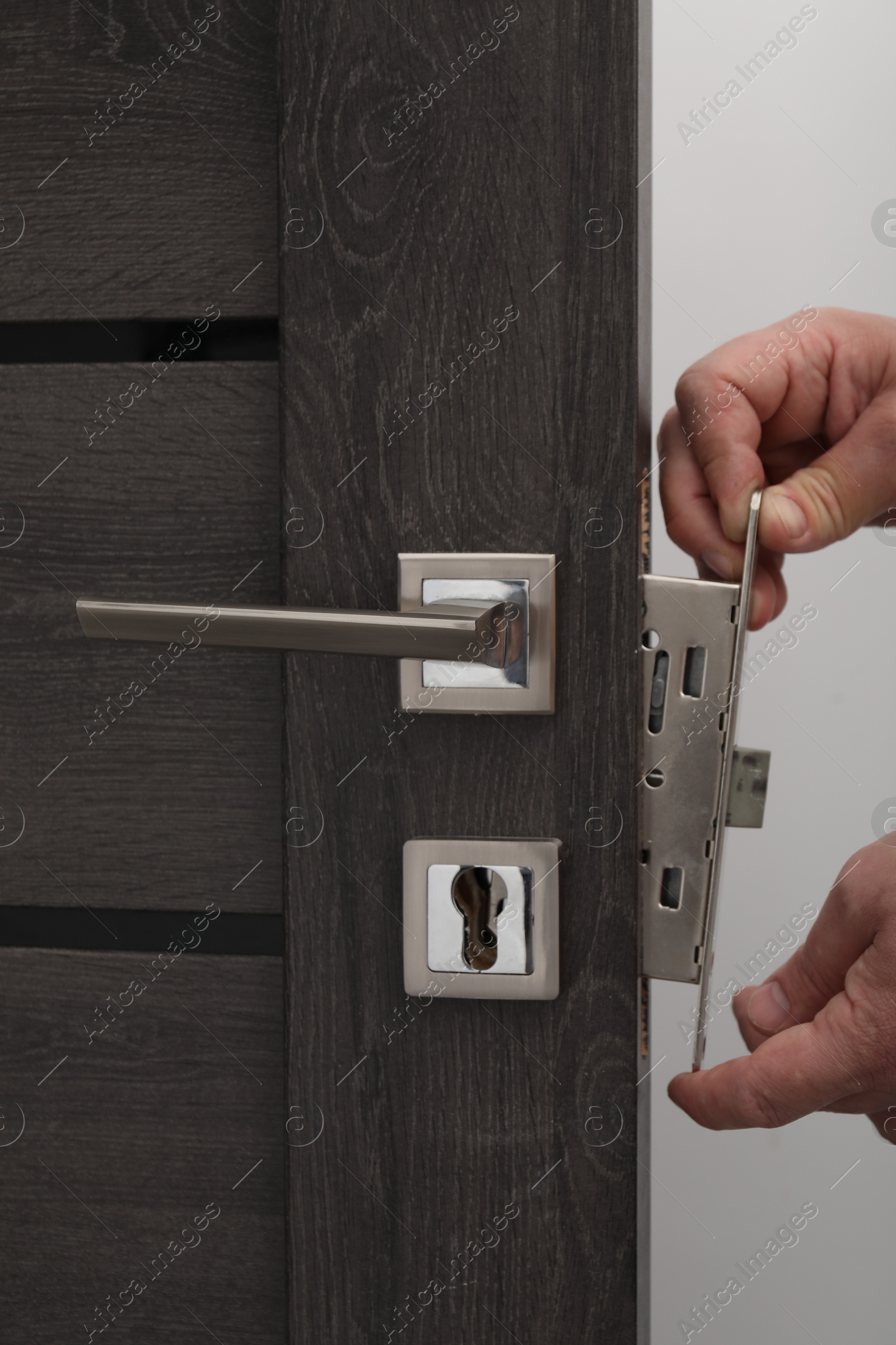 Photo of Handyman changing door handleset indoors, closeup view