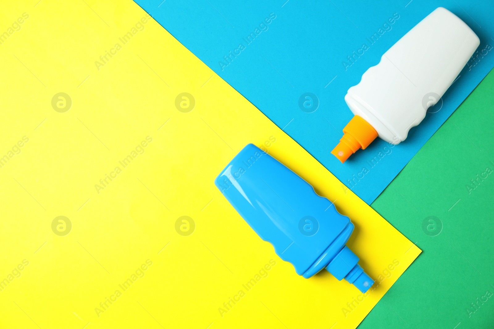 Photo of Bottles of sun protection body cream on color background, top view with space for text