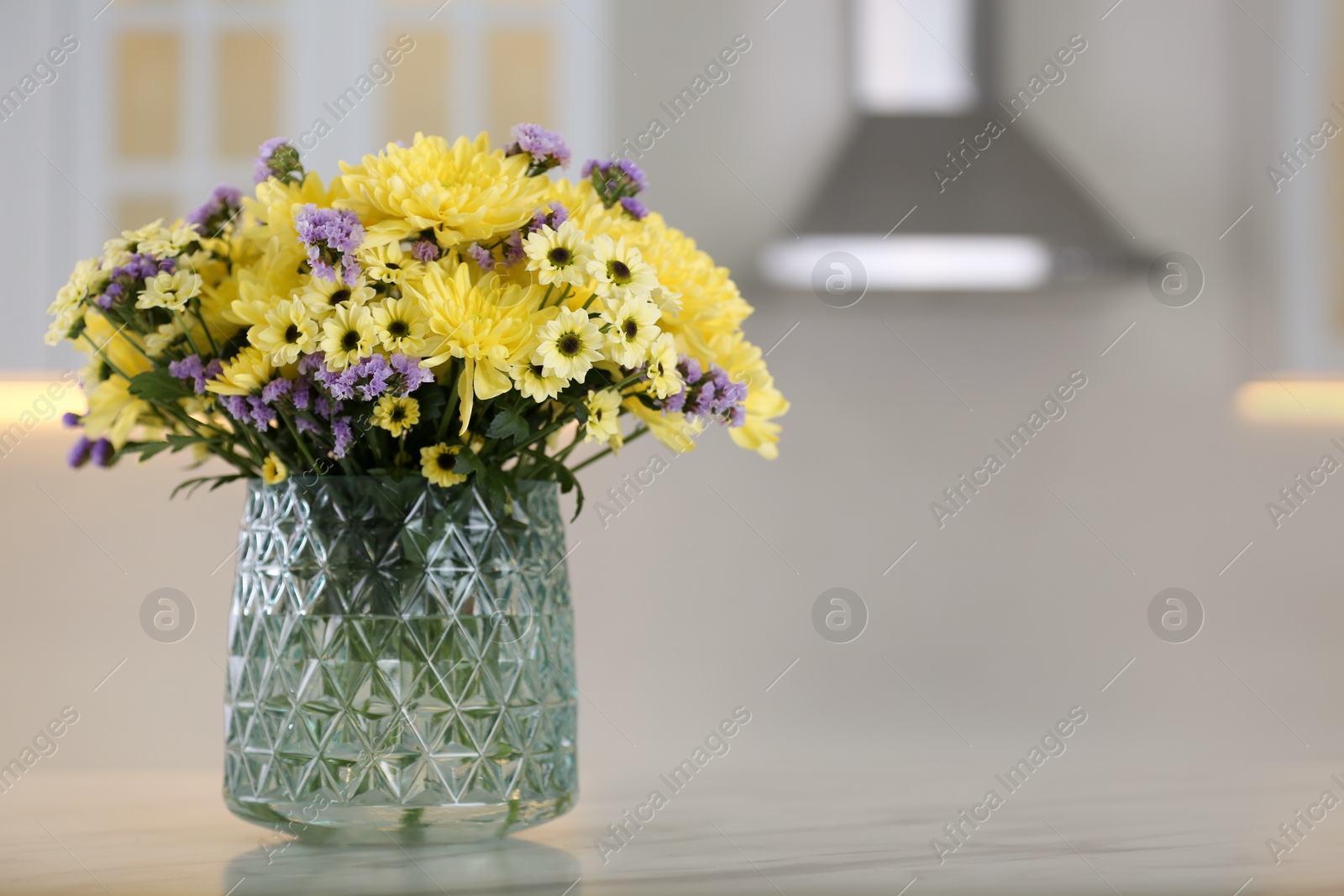 Photo of Vase with beautiful chrysanthemum flowers on table in kitchen, space for text. Interior design