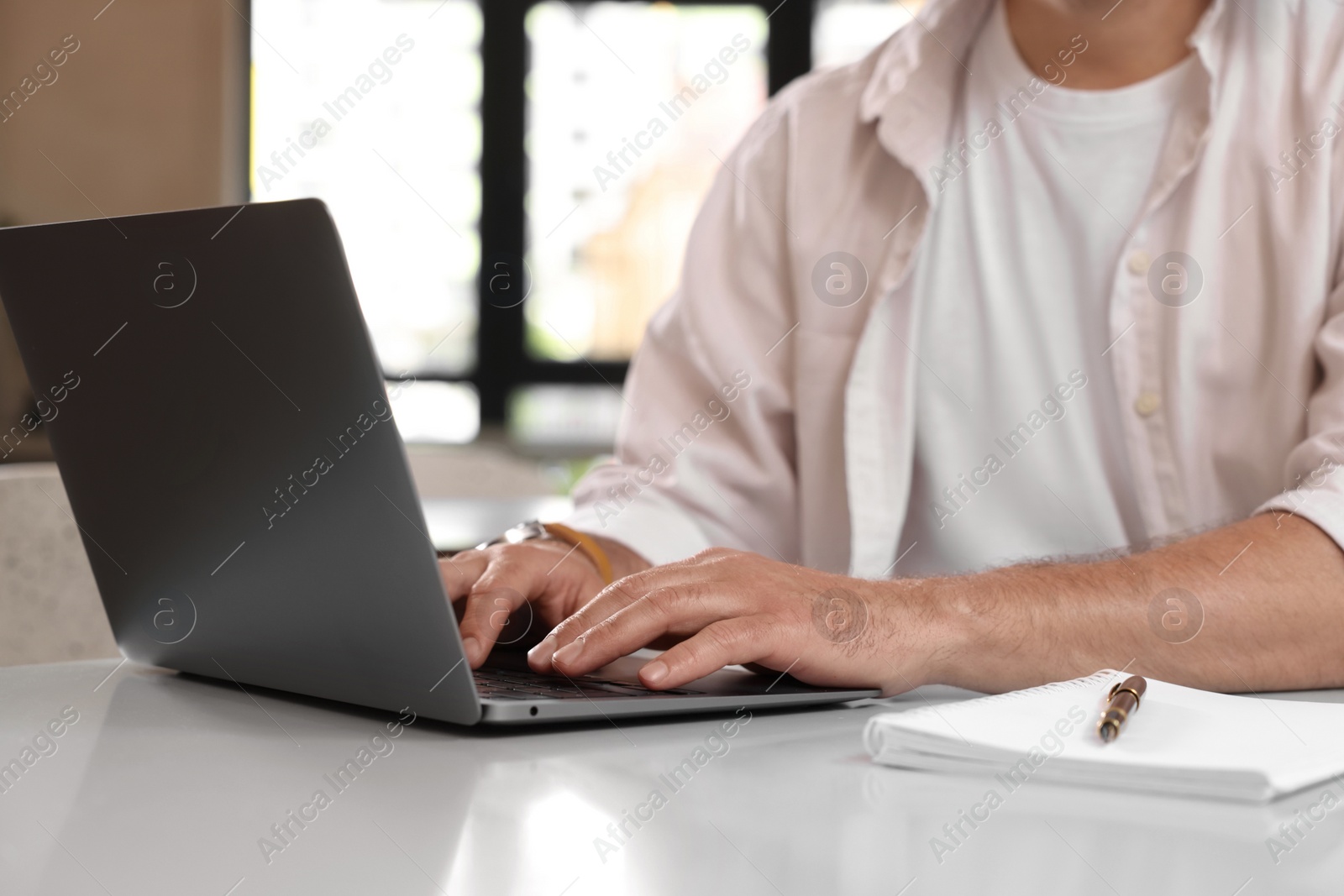 Photo of Man working on laptop at table in cafe, closeup