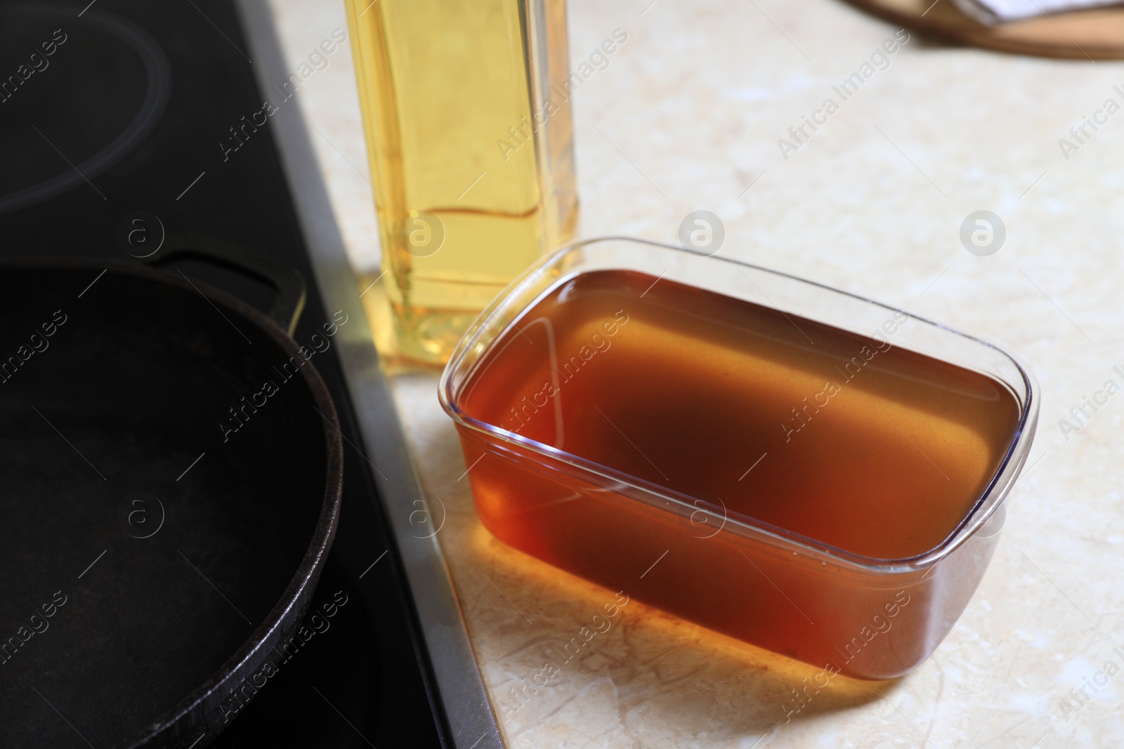 Photo of New and used cooking oil near stove on kitchen counter