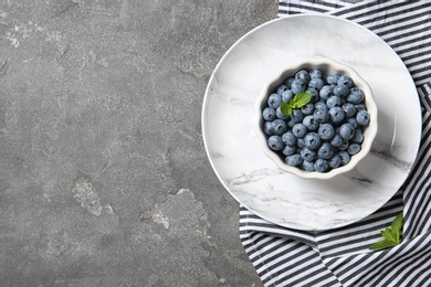 Photo of Dishware with juicy blueberries and space for text on color table, top view