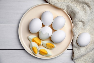 Photo of Plate with hard boiled eggs on white wooden table, flat lay