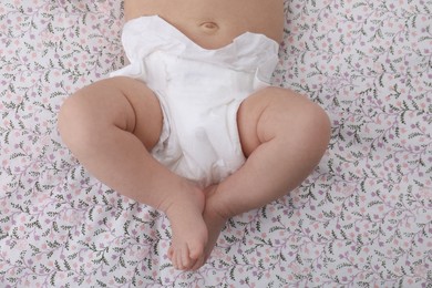 Photo of Little baby in diaper on bed, top view
