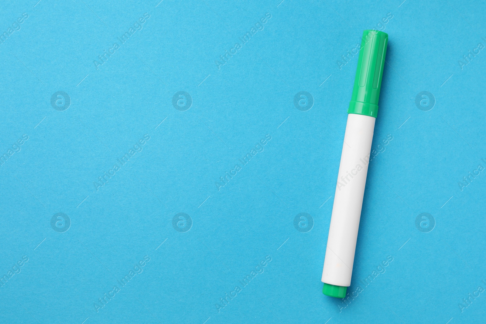 Photo of Bright green marker on light blue background, top view. Space for text