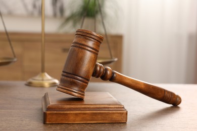 Photo of Wooden gavel and sound block on table indoors, closeup