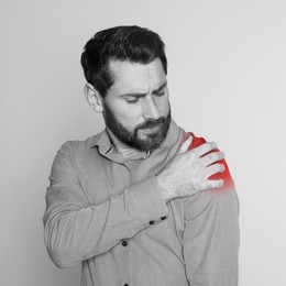 Man suffering from rheumatism on light background. Black and white effect with red accent in painful area