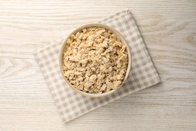 Photo of Tasty boiled oatmeal in bowl on light wooden table, top view