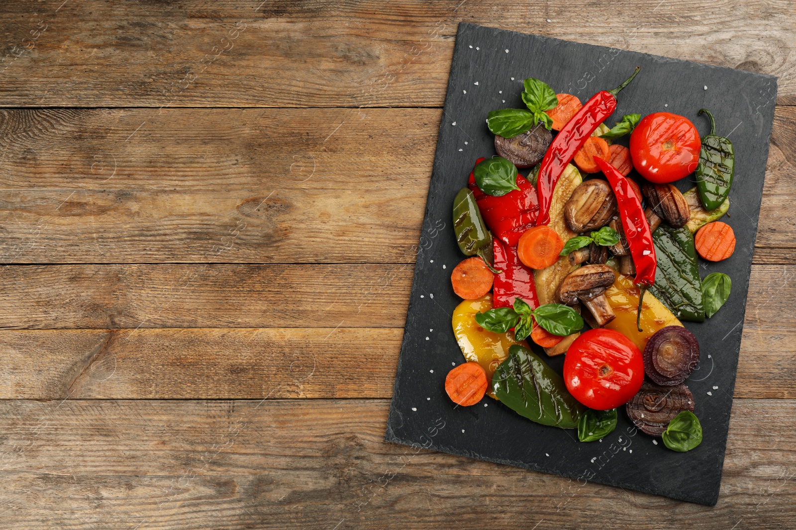 Photo of Delicious grilled vegetables on wooden table, top view. Space for text