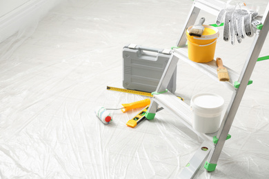 Photo of Stepladder and different tools in room, space for text. Interior renovation