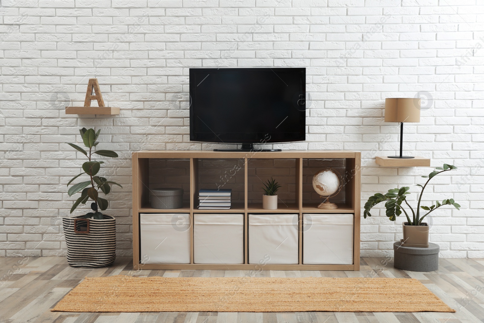 Photo of Modern TV set near white brick wall in living room