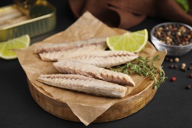 Photo of Canned mackerel fillets served on black table, closeup
