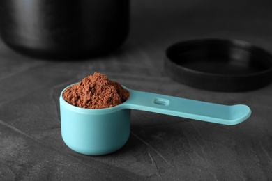 Photo of Scoop of chocolate protein powder on grey stone table