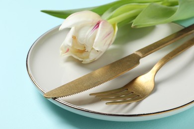 Photo of Stylish table setting with cutlery and tulips on light blue background