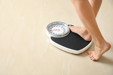 Woman stepping on floor scales indoors, space for text. Overweight problem