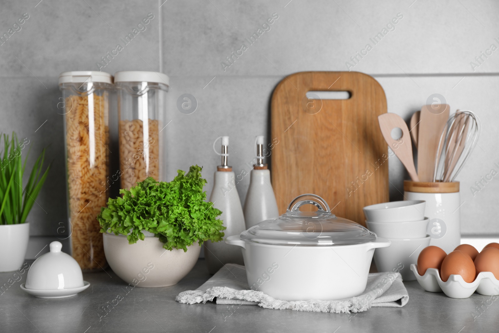 Photo of Set of different cooking utensils and products on grey countertop in kitchen