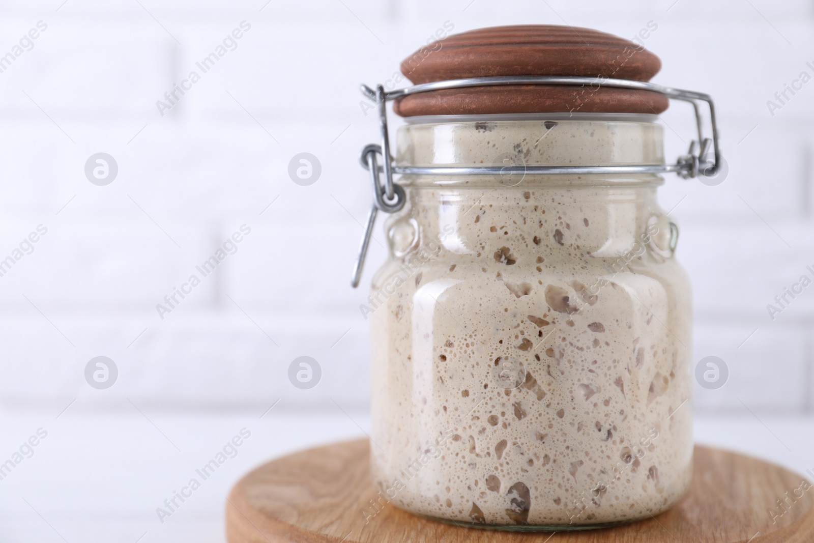 Photo of Sourdough starter in glass jar on table, space for text