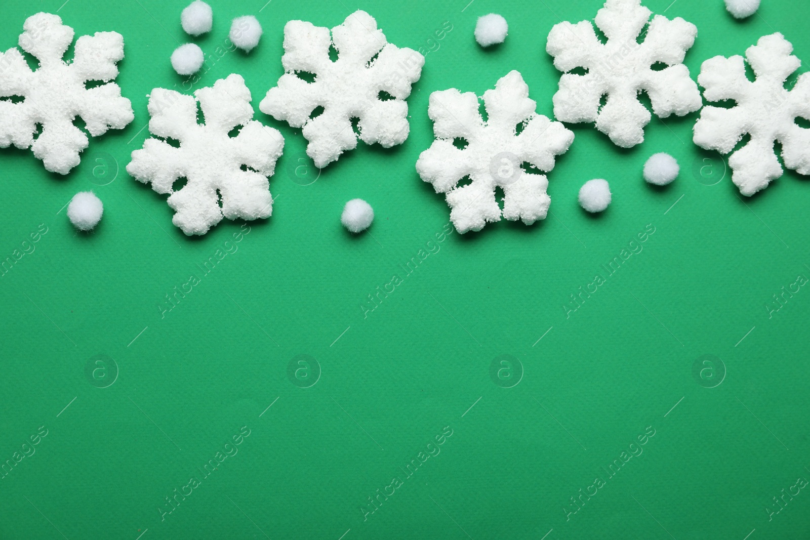 Photo of Beautiful decorative snowflakes on green background, flat lay. Space for text