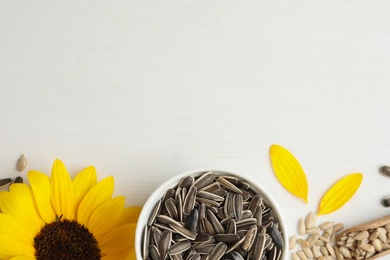 Photo of Organic sunflower seeds on white wooden table, flat lay. Space for text