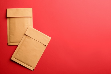 Photo of Kraft paper envelopes on red background, flat lay. Space for text