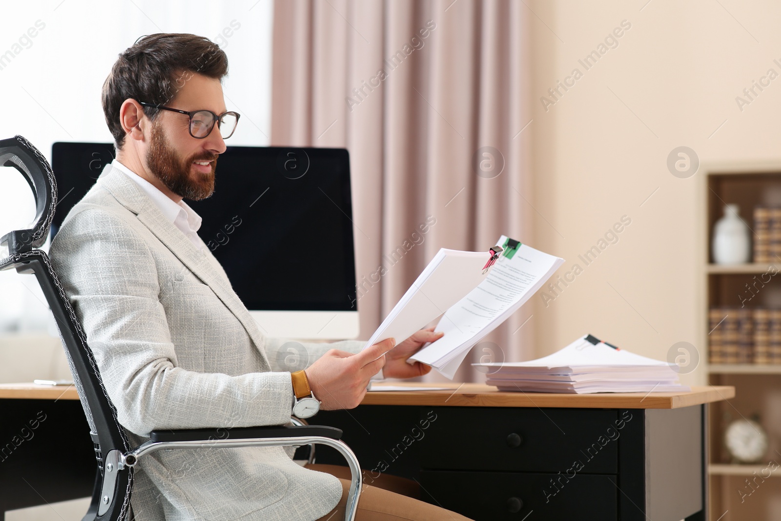 Photo of Happy businessman working with documents at wooden table in office