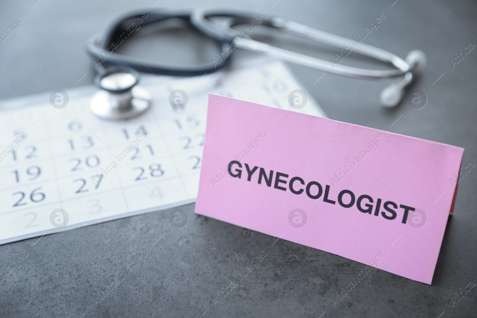 Photo of Card with word GYNECOLOGIST near calendar on table