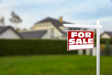 Image of Sale sign near beautiful house outdoors. Red signboard with words