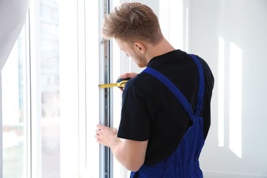 Photo of Service man measuring window for installation indoors