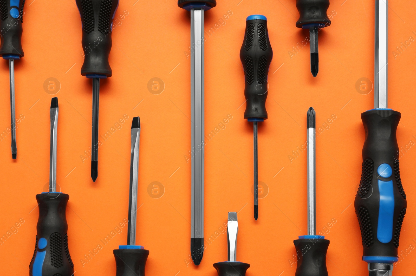 Photo of Set of screwdrivers on orange background, flat lay