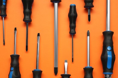 Set of screwdrivers on orange background, flat lay