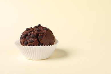 Photo of Tasty chocolate muffin on beige background, space for text