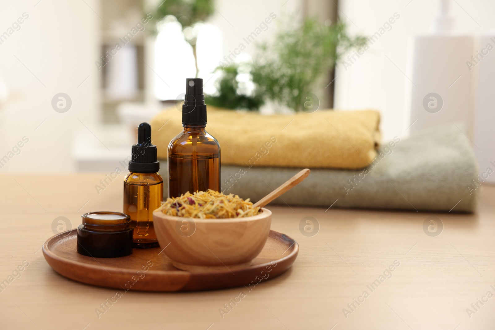 Photo of Dry flowers, bottles of essential oils and jar with cream on wooden table indoors, space for text. Spa time