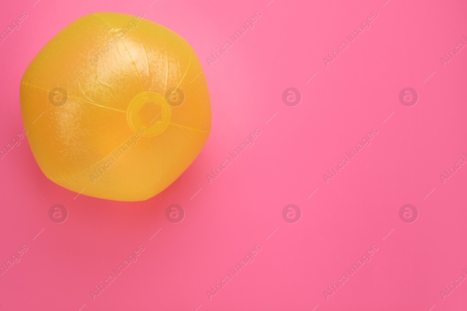 Photo of Bright beach ball on pink background, top view. Space for text