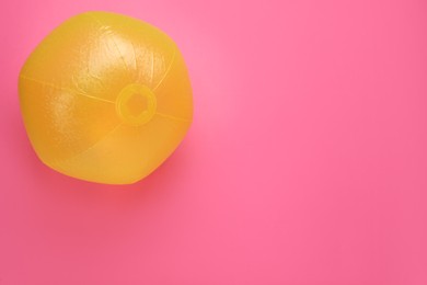 Bright beach ball on pink background, top view. Space for text
