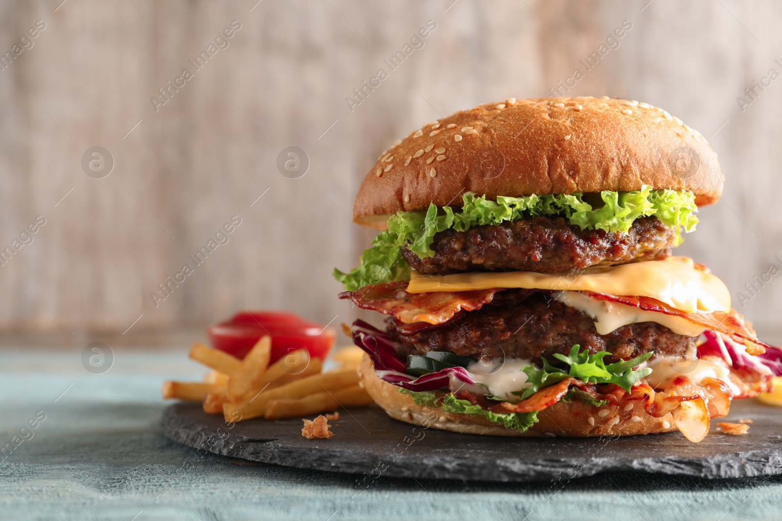 Photo of Tasty double burger with bacon on slate plate