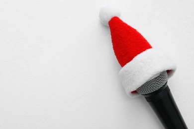 Photo of Top view of microphone with Santa hat on white table, space for text. Christmas music