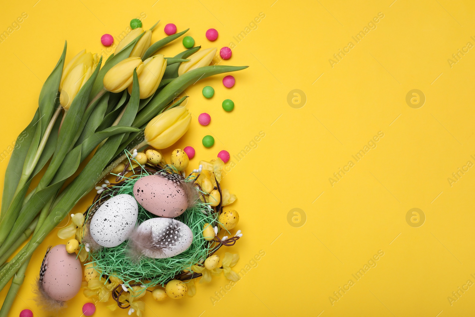 Photo of Flat lay composition with beautiful flowers and eggs on yellow background space for text. Easter celebration