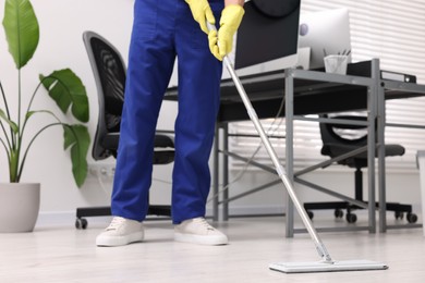 Photo of Cleaning service worker washing floor with mop in office, closeup