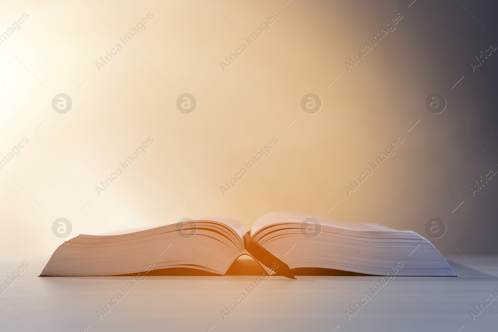 Photo of Open Bible on white wooden table against beige background. Space for text