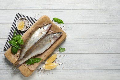 Photo of Fresh raw pike perches and ingredients on white wooden table, flat lay with space for text. River fish