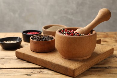 Photo of Different sorts of aromatic pepper on wooden table