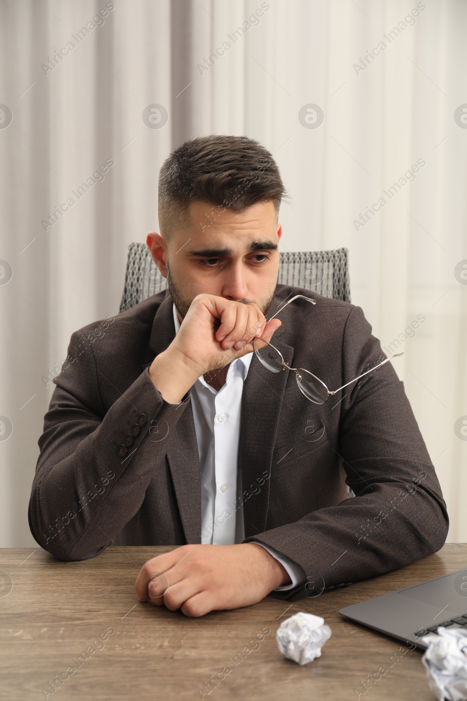 Photo of Sad businessman sitting at table in office