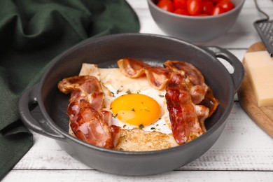 Photo of Delicious crepe with egg and bacon in dish on white wooden table. Breton galette