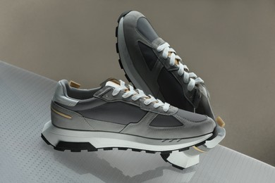 Photo of Stylish presentation of trendy sneakers against grey background