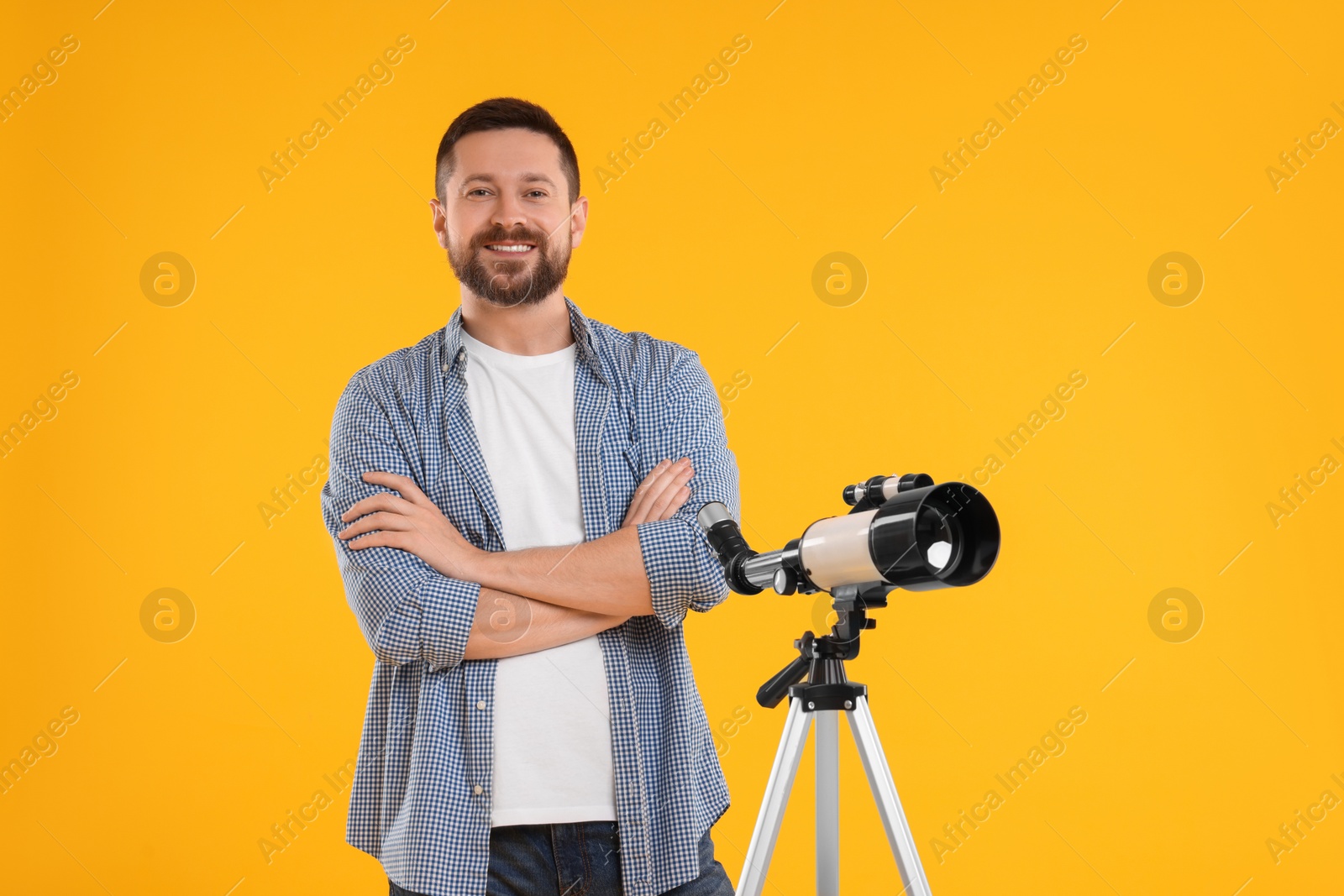 Photo of Happy astronomer with telescope on orange background