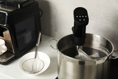 Photo of Sous vide cooker and vacuum packing in pot. Thermal immersion circulator