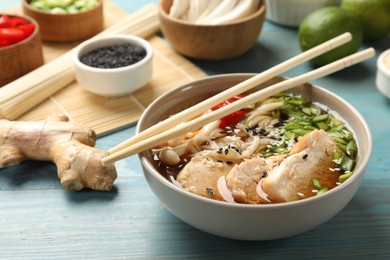 Photo of Delicious ramen with meat and ingredients on light blue wooden table. Noodle soup