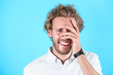 Photo of Handsome young man laughing on color background